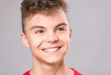 Close up emotional portrait of caucasian teen boy. Handsome smiling guy. Funny cut teenager on gray background. Happy child looking away.