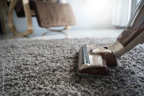 Slika na platnu Close-up  man using a vacuum cleaner while cleaning in the room