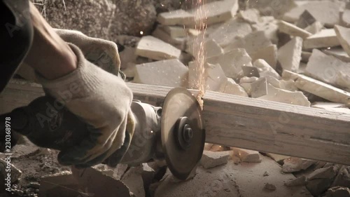 Dismantling of the walls of the destroyed house. Worker with metal-cutting angle grinder. Super slow motion 240 fps.