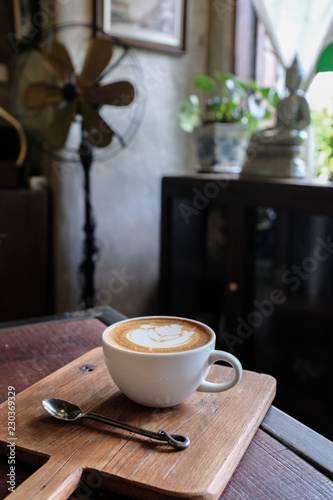 Fototapeta Naklejka Na Ścianę i Meble -  A cup of cafe latte coffee in white ceramic cup on wooden tray and stainless spoon in a traditional thai house on blurred background