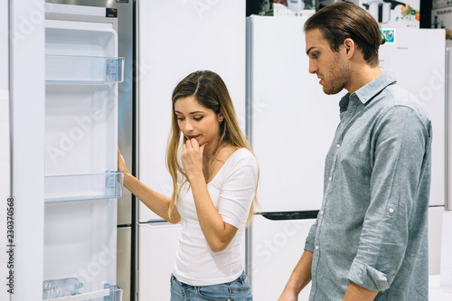 Couple of friends choosing a fridge in a store