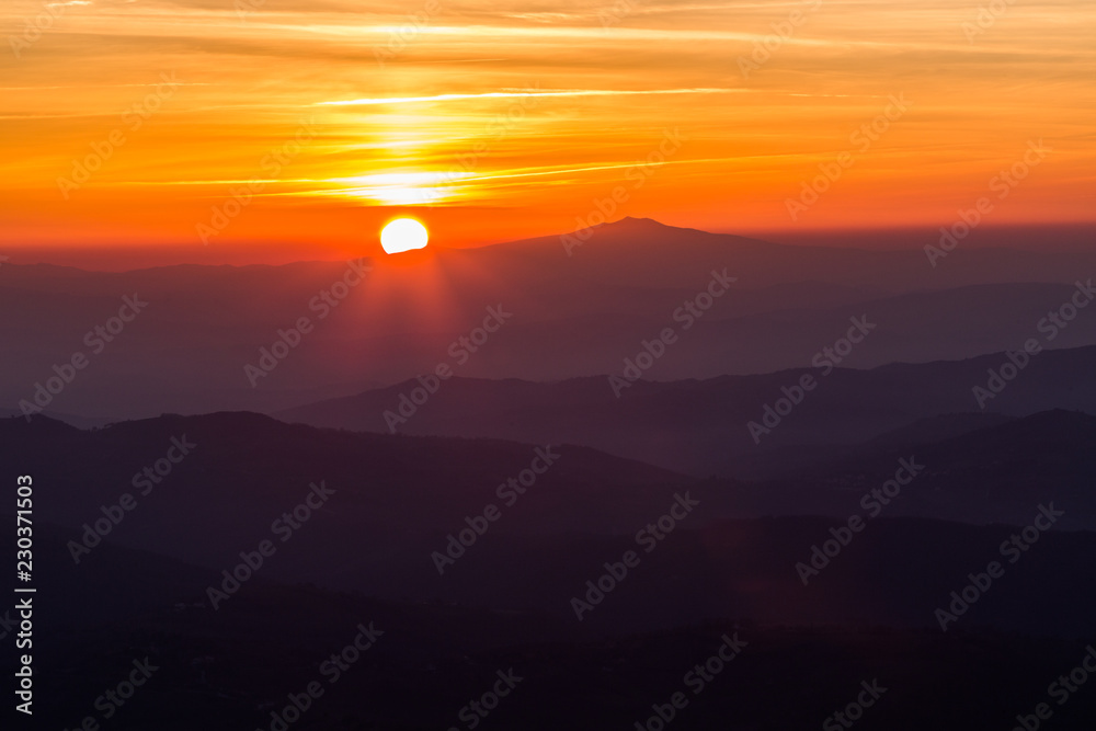 Beautiful sunset with sun coming down behind various layers of mountains