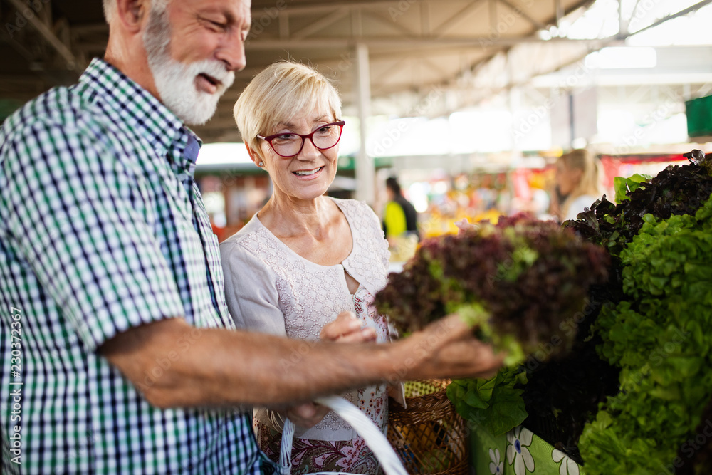 Smiling senior couple buying vegetables and at the merket Smiling senior couple buying vegetables and at the merket