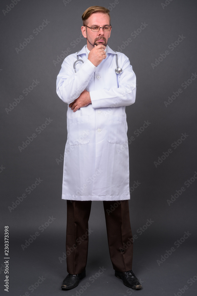 Blond bearded man doctor with goatee against gray background Blond bearded man doctor with goatee against gray background