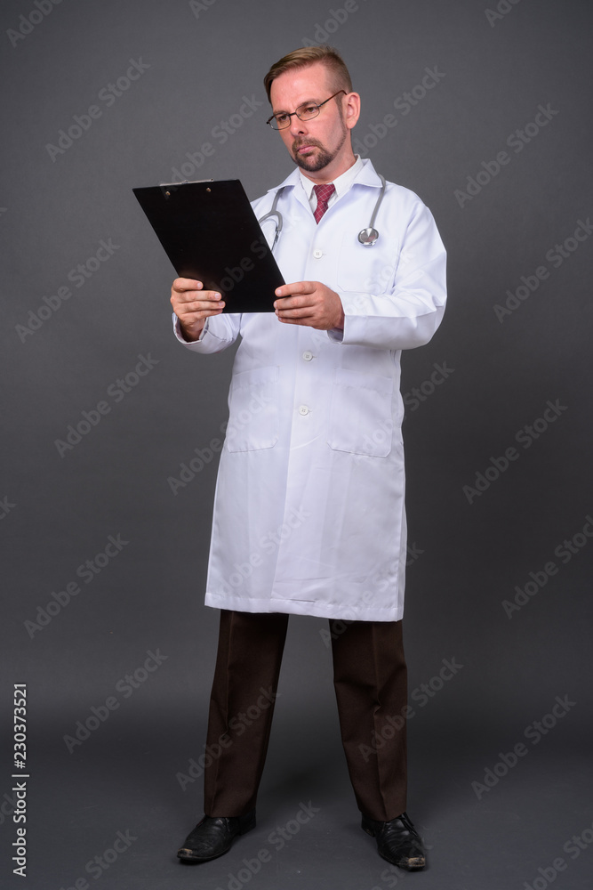Blond bearded man doctor with goatee against gray background Blond bearded man doctor with goatee against gray background