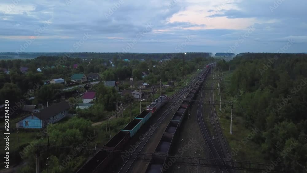 Freight train with empty cars leaving distance by rail at sunset, aerial shot Freight train with empty cars leaving distance by rail at sunset, aerial shot