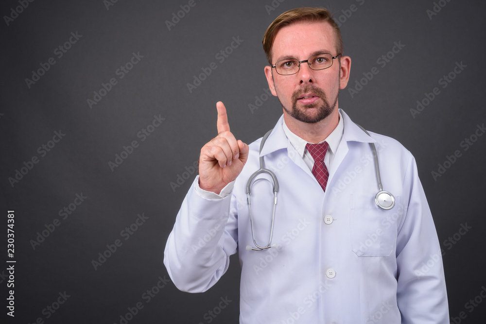 Blond bearded man doctor with goatee against gray background Blond bearded man doctor with goatee against gray background