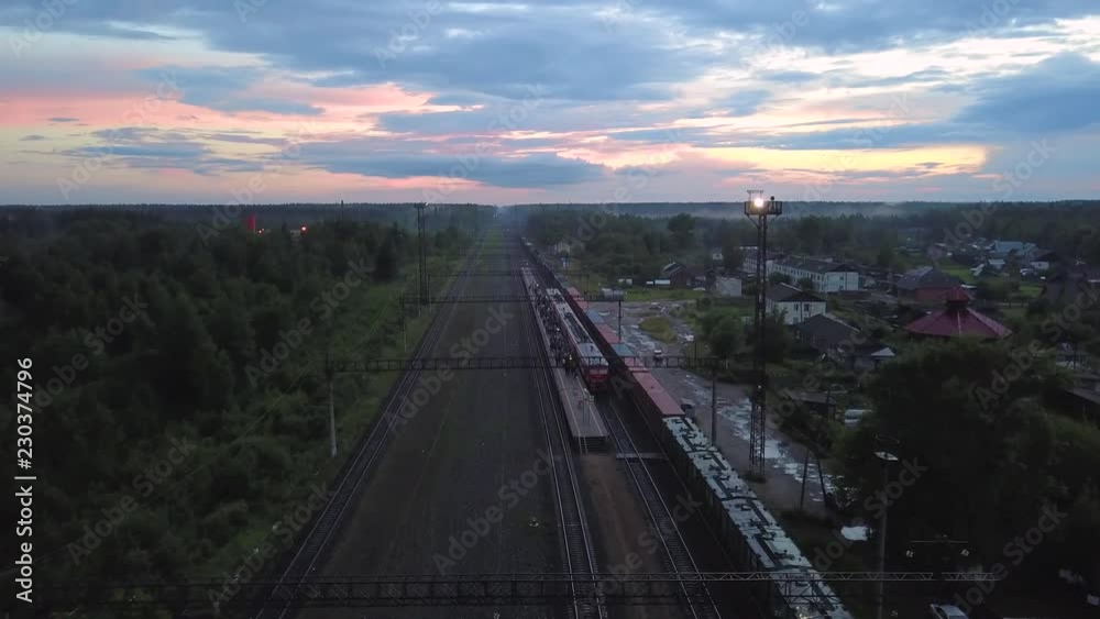 Passenger train stopped at the platform in the village, aerial shot Passenger train stopped at the platform in the village, aerial shot