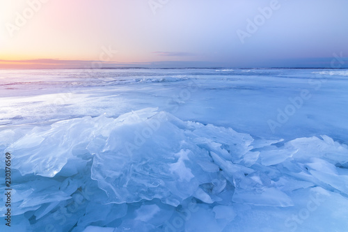 dawn at the frozen lake shore   in the direction of the sun