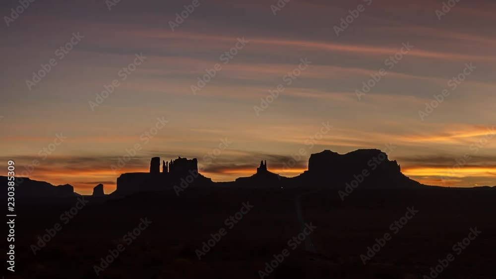 Silhouette of the famous Monument Valley rock formations after sunset with a dramatic sky and lights of cars moving on Highway 163. time lapse Silhouette of the famous Monument Valley rock formations after sunset with a dramatic sky and lights of cars moving on Highway 163. time lapse