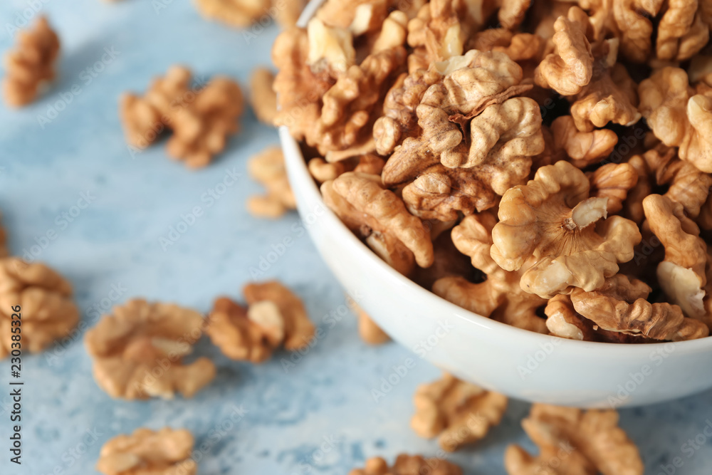 Bowl with tasty walnuts on color table, closeup Bowl with tasty walnuts on color table, closeup