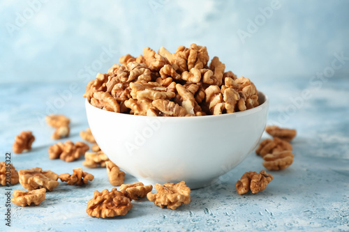 Bowl with tasty walnuts on color table photo