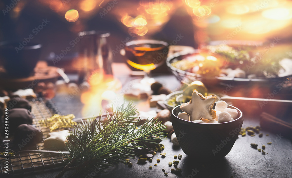 Home holidays cuisine and sweet gifts making for Christmas. Mug with marshmallows and cinnamon star Christmas cookie on table with nuts , chocolate and fir brunches. Cozy festive homely atmosphere Home holidays cuisine and sweet gifts making for Christmas. Mug with marshmallows and cinnamon star Christmas cookie on table with nuts , chocolate and fir brunches. Cozy festive homely atmosphere