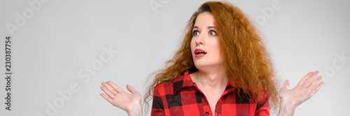 A girl in a plaid shirt spreads her arms out to the sides. Young girl with red hair photo