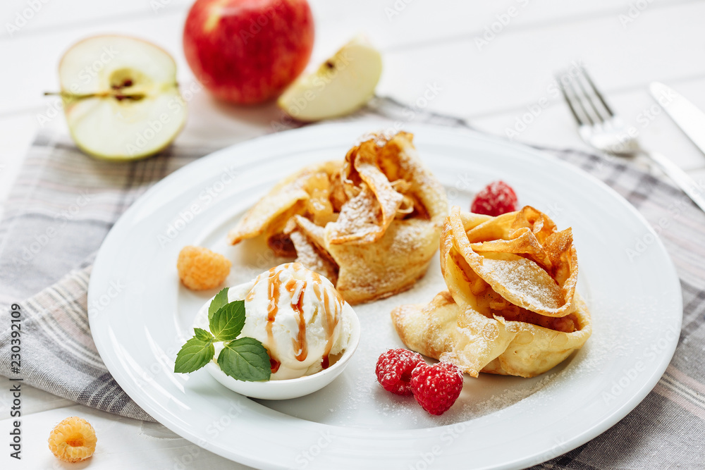 Crepes, thin pancakes with fresh strawberry and ice-cream, on white plate. Wooden background. Top view