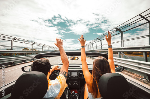 Happy couple driving a convertible car enjoying vacation having fun on the road photo