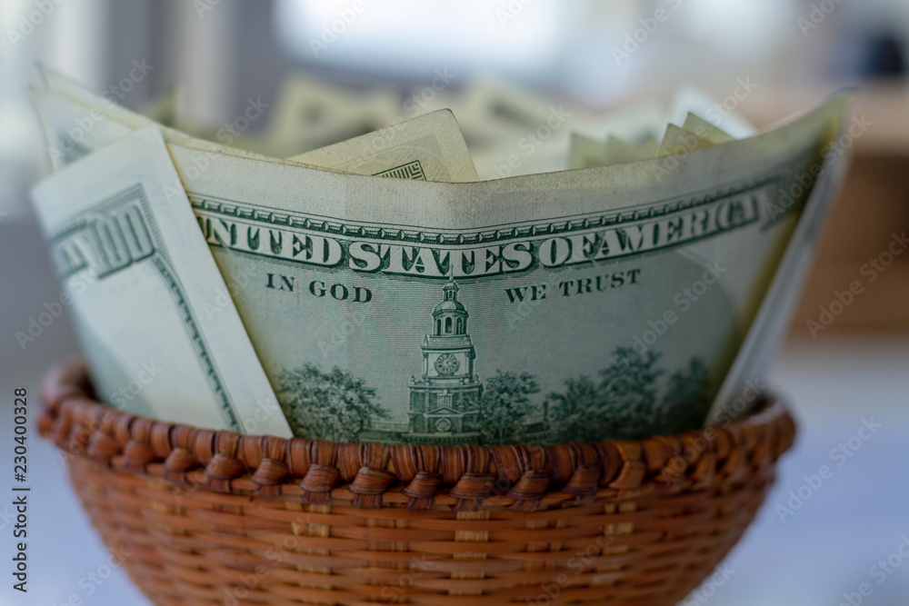 Obraz premium Full wicker basket with money. A lot of cash. Lots of green cash in a wicker basket for small expenses. Cash American dollars closeup with blur and bokeh effect.