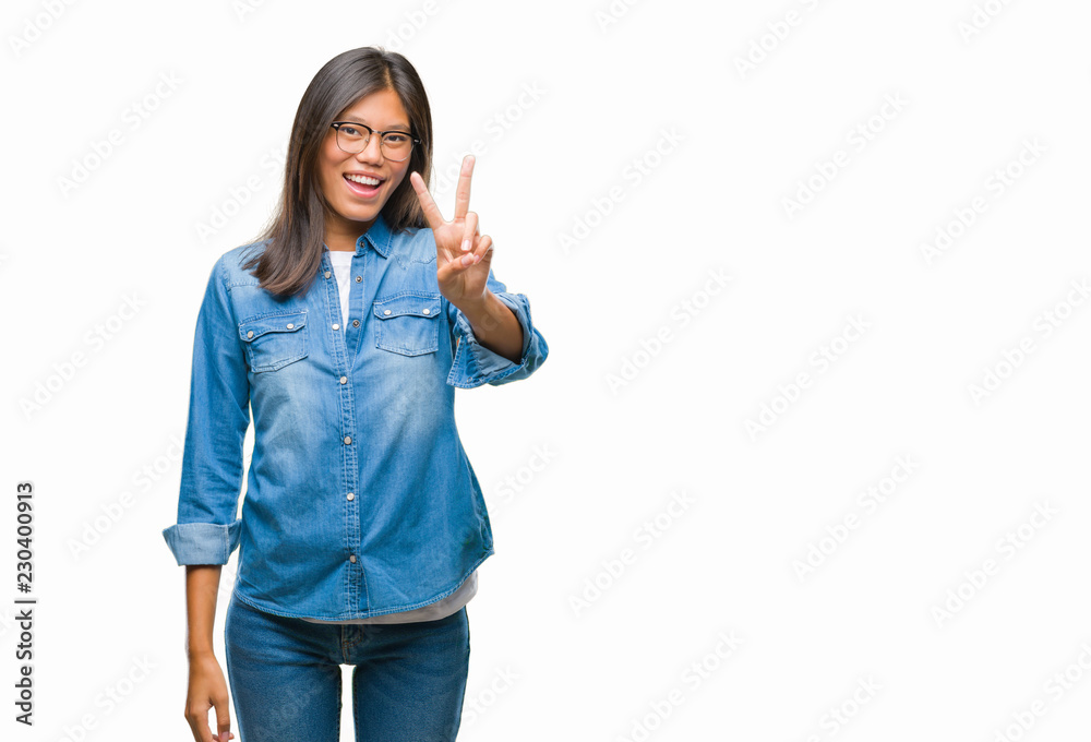 Young asian woman wearing glasses over isolated background smiling with happy face winking at the camera doing victory sign. Number two. Young asian woman wearing glasses over isolated background smiling with happy face winking at the camera doing victory sign. Number two.