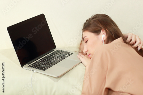 young woman listen to music from computer and fall asleep on sofa in living room
