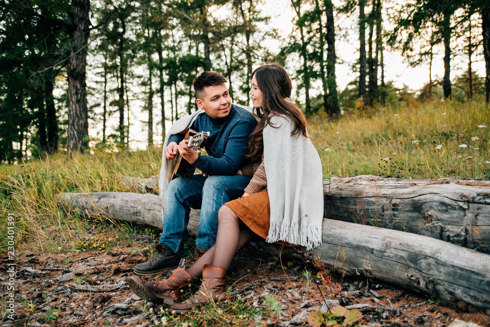 young man playing guitar while woman smiling on meadow
