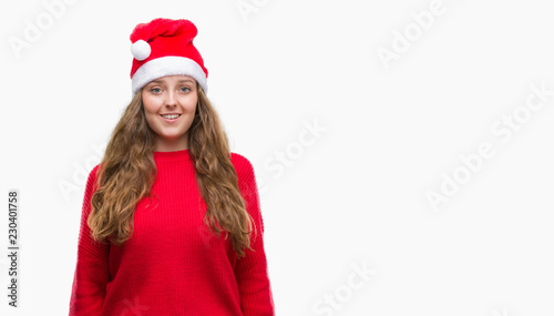 Young blonde woman wearing santa claus hat with a happy face standing and smiling with a confident smile showing teeth
