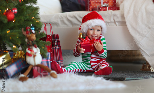 appy baby boy  in pajamas with gifts on christmas morning near   tree