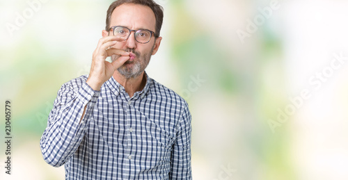 Handsome middle age elegant senior man wearing glasses over isolated background mouth and lips shut as zip with fingers. Secret and silent, taboo talking