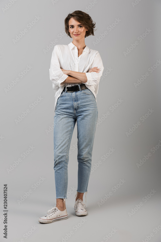 Fototapeta premium Szczęśliwy młody biznes kobieta pozowanie na białym tle na tle szarej ścianie.