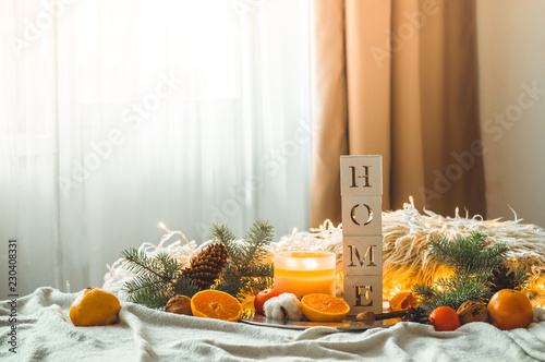 The word HOME and Tangerines in a winter composition  Christmas trees  candles  cones  cotton. Symbol of New Year and Christmas
