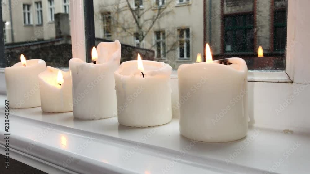Group of burning white candles in window in winter Stock Video Adobe Stock