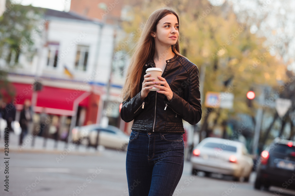 Beautiful woman holding paper coffee cup and enjoying a walk in the city