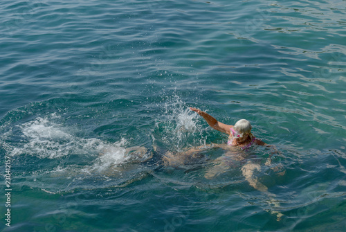 Two women are swimming with splash playing in sea water.