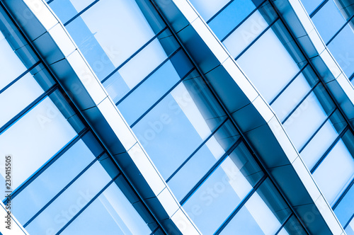 Wall of glass office building shot diagonally. Light blue toning.