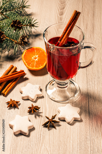 Glass of Christmas mulled wine with spices, orange and cookies on wooden boards