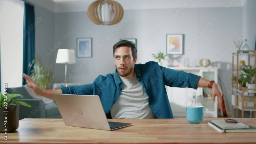 Handsome Happy Man Does Funny Dance Routine while Sitting at His Desk in the Living Room. Handsome Happy Man Does Funny Dance Routine while Sitting at His Desk in the Living Room.