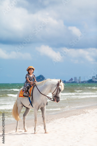 Close up portrait of kids and horse . little girl ride a horse and Tenderness and caring for White horse On the beach.