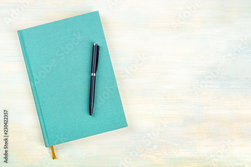 A photo of a teal blue journal with a pen, an elegant diary, notebook or planner, shot from above with copy space photo