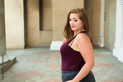 Beautiful overweight woman posing on city street. © nagaets