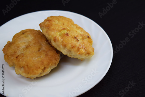Delicious cutlets on a white plate on a black background.