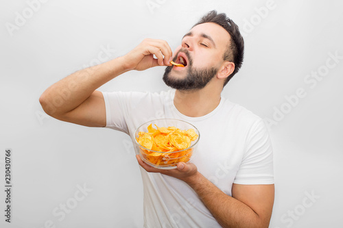 Fototapet Man in white shirt stands and eats chips