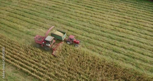 Aerial footage of corn harvest with combine and tractor on a fieldon a field photo