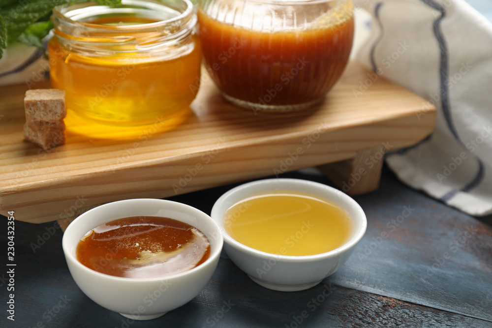 Bowls and jars of tasty honey on table, closeup Bowls and jars of tasty honey on table, closeup