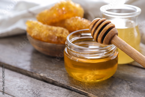 Full jar of honey with dipper on wooden table