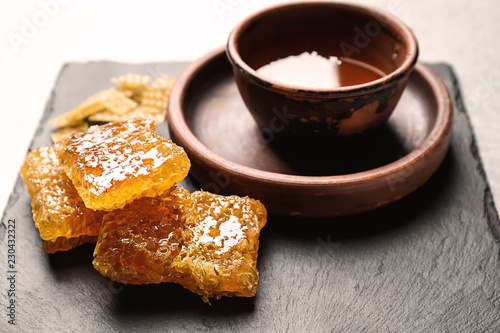 Bowl with honey and combs on slate plate