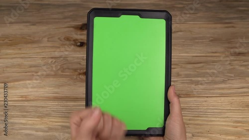 A woman holds a tablet PC with a green screen for your own custom content.