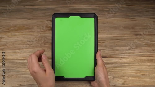 A woman holds a tablet PC with a green screen for your own custom content.