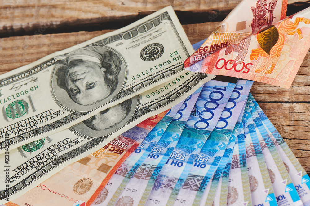 Obraz premium Dollars and tenge on a wooden background. Kazakhstan currency. Business and money..