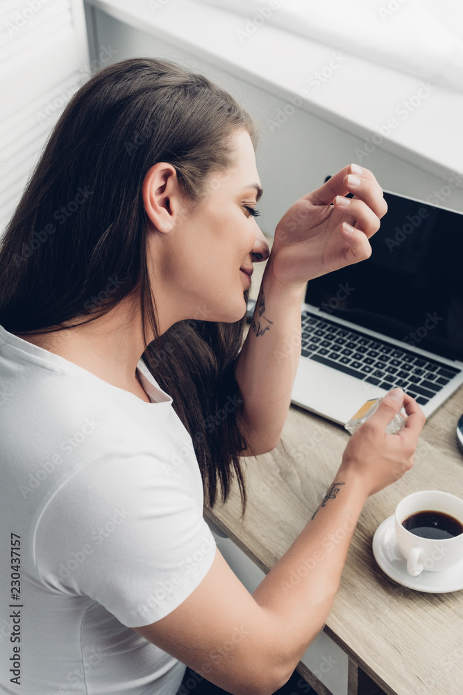 young transgender man smelling perfume on wrist at home young transgender man smelling perfume on wrist at home