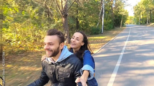 Happy couple riding on the scooter. Man driving, woman holding selfiestick and shooting video on the actioncamera. photo