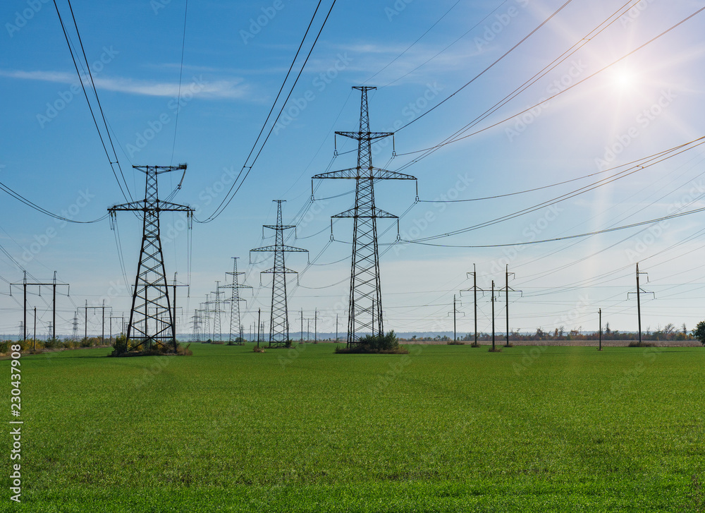 Electrical net of poles on a panorama of blue sky and green meadow Electrical net of poles on a panorama of blue sky and green meadow